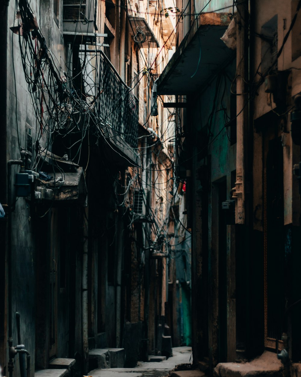 a narrow alleyway in a city with lots of wires