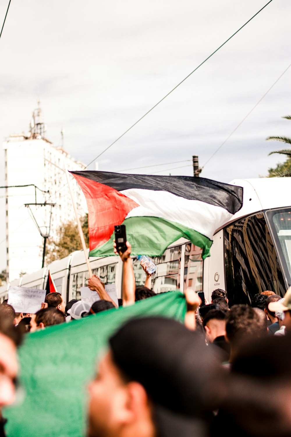 a crowd of people holding a flag and a bus