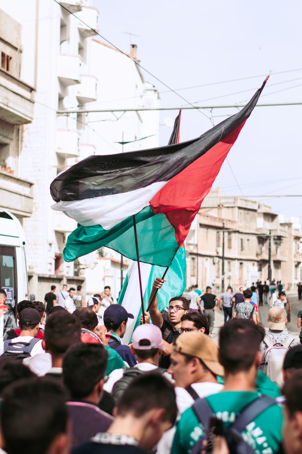 a crowd of people walking down a street holding flags