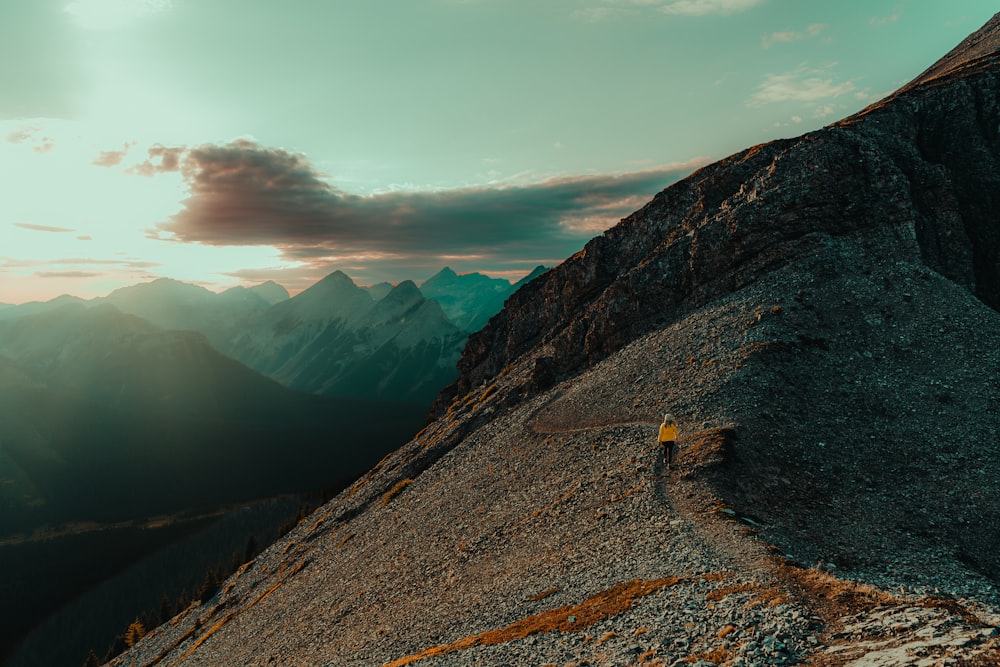 a person hiking up a mountain with the sun setting in the background