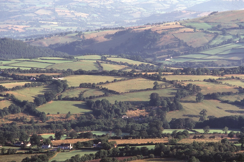 an aerial view of a valley with rolling hills in the background