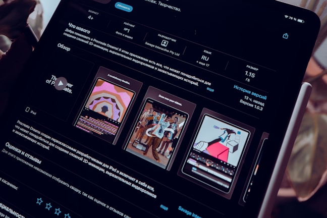 A close-up view of an iPad screen displaying an application interface in dark mode, featuring text in Russian and several graphics related to the app. The screen includes sections for ratings, language, size, and version history. There are preview images showcasing artistic designs and animations.