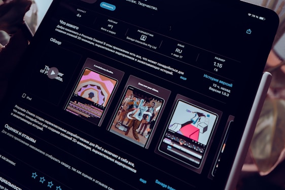 A close-up view of an iPad screen displaying an application interface in dark mode, featuring text in Russian and several graphics related to the app. The screen includes sections for ratings, language, size, and version history. There are preview images showcasing artistic designs and animations.