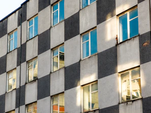 A sleek, dark grey minimalist building facade with natural stone textures under soft daylight