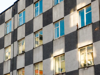 A sleek, dark grey minimalist building facade with natural stone textures under soft daylight