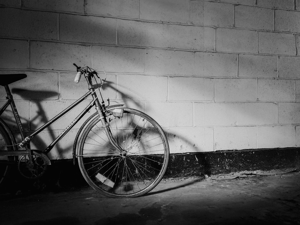a black and white photo of a bike leaning against a wall