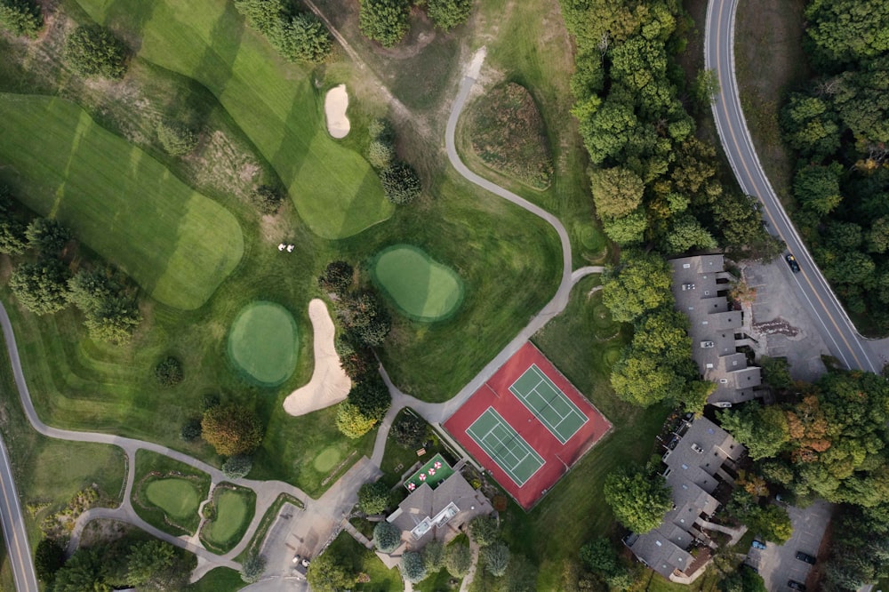 an aerial view of a golf course with a red tennis court