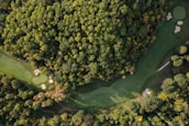 An aerial view of a beautifully designed golf course surrounded by trees and water features.