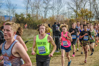 Three runners from different tribes crossing a natural mountain trail together.