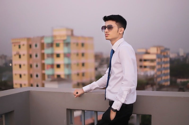 a man in a white shirt and tie standing on a balcony