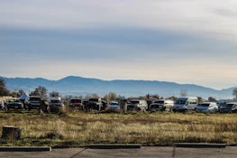 A row of rental cars lined up with a mountain landscape in the background.