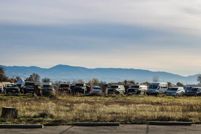 An array of vehicles parked neatly outside a modern rental office with mountains in the background.
