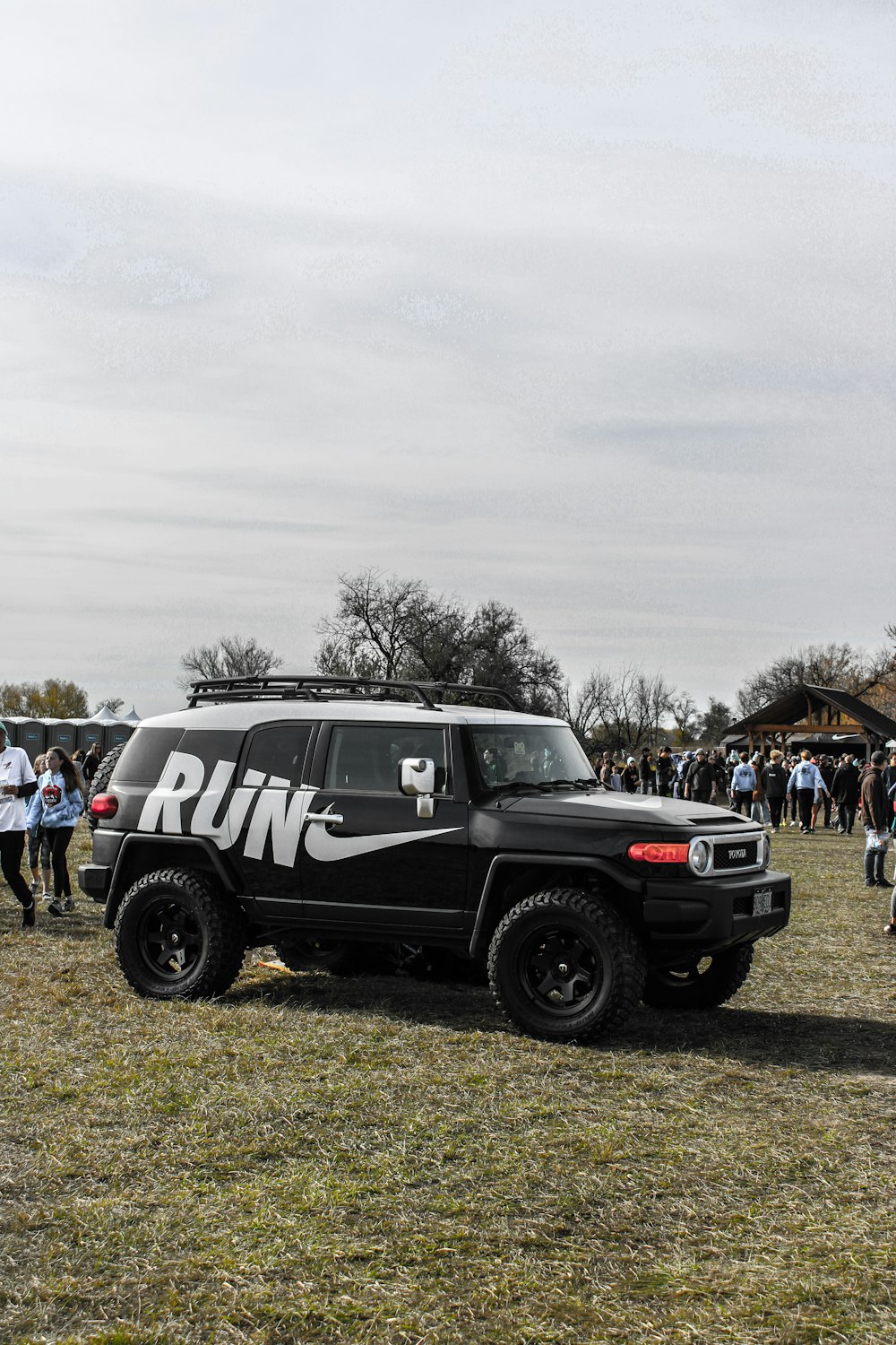 a group of people standing around a black jeep