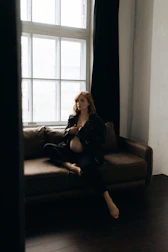 A graceful woman lounging on a velvet sofa, bathed in warm light.