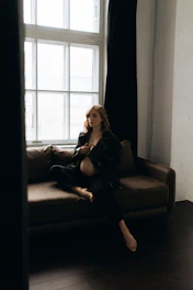 An Indian woman sitting peacefully in a cozy room, journaling with soft natural light filtering through sheer curtains.