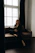 A serene woman sitting peacefully in a cozy room with soft natural light filtering through the window.