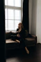 A serene woman sitting peacefully in a cozy room with soft natural light filtering through the window.