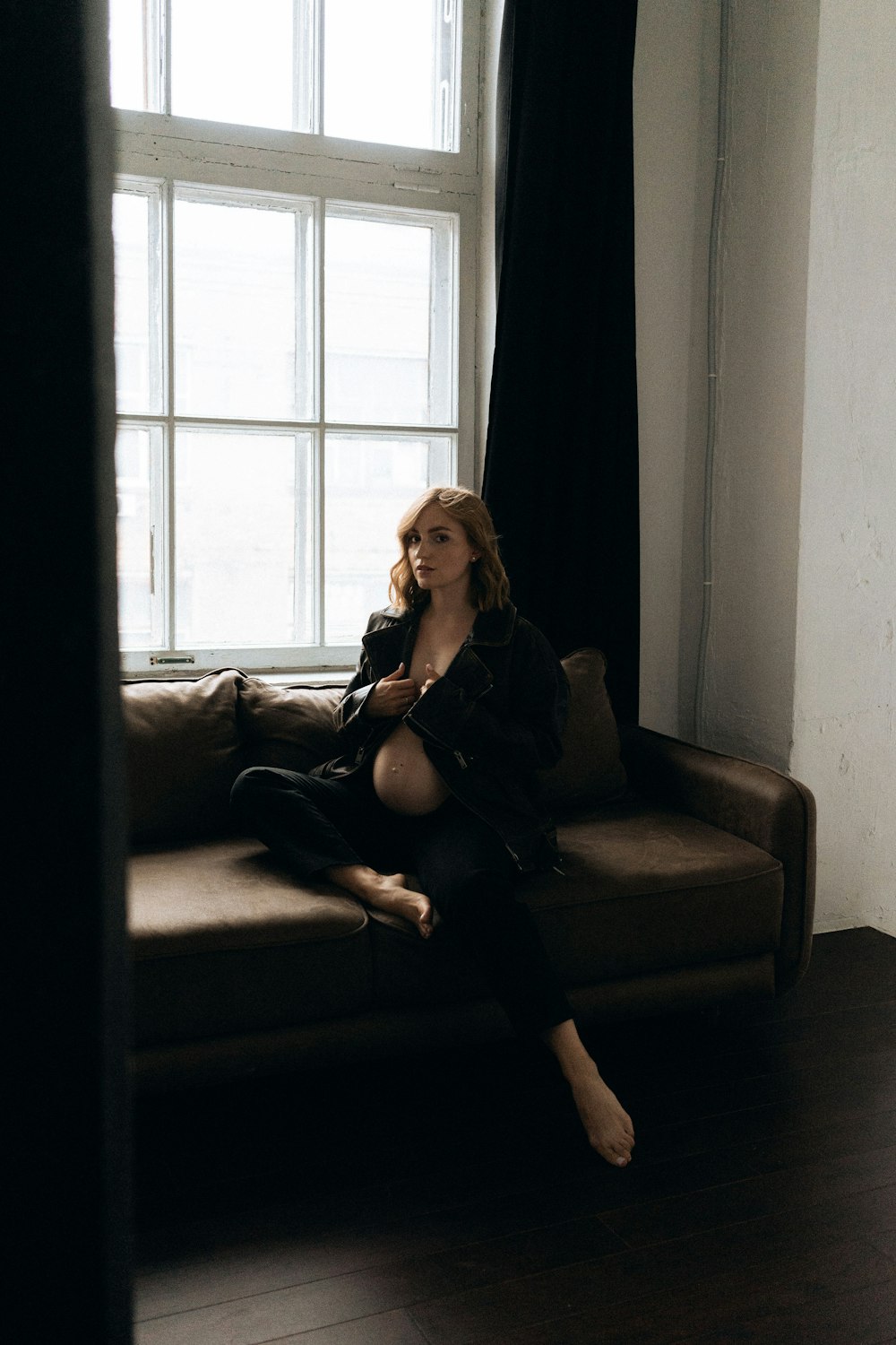 a woman sitting on a couch in front of a window