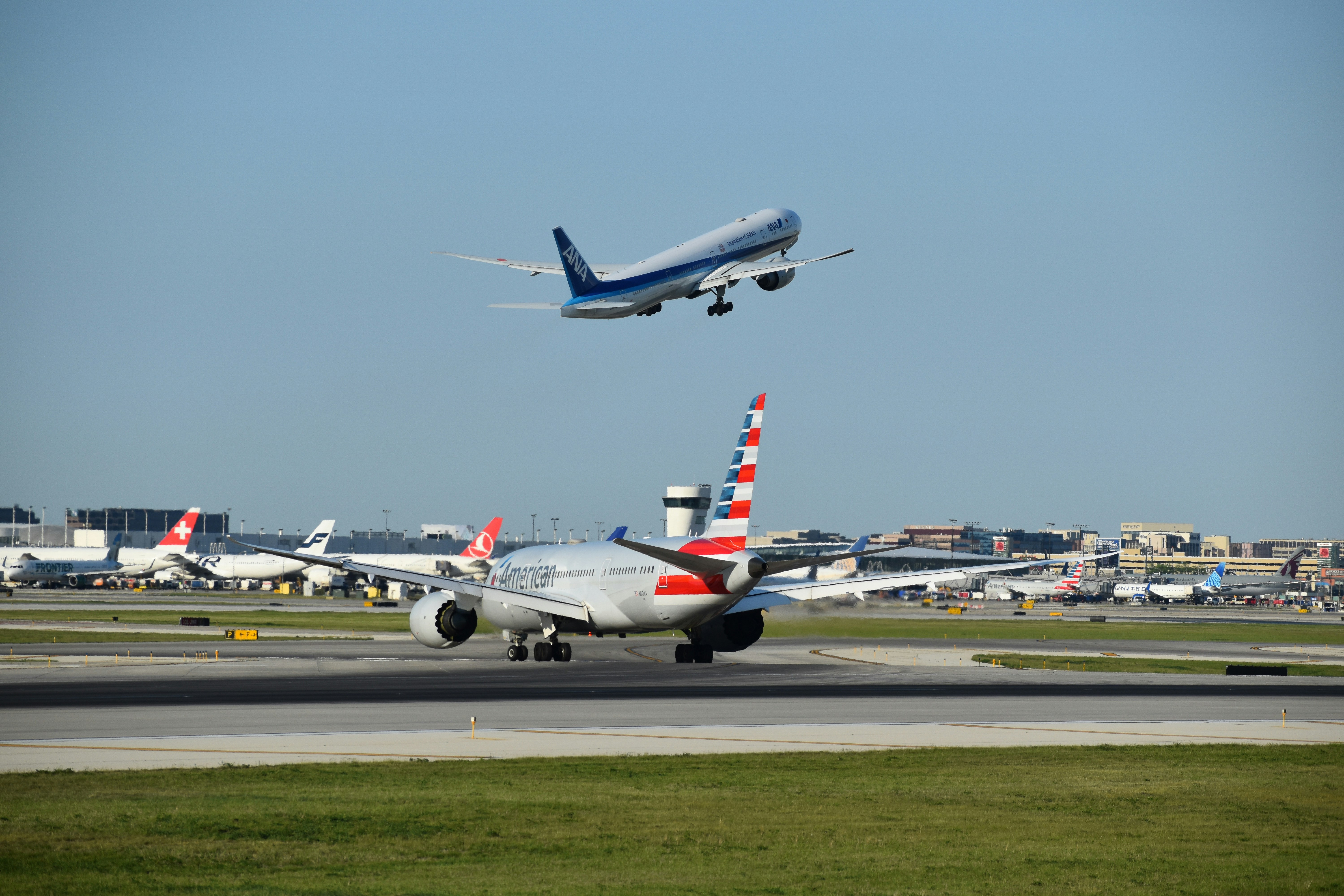 a large jetliner flying over an airport runway, O