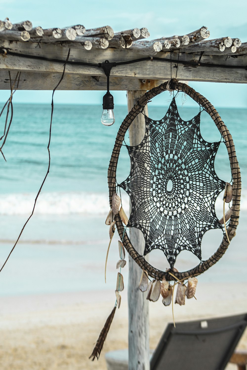 a black and white dream catcher hanging from a wooden structure