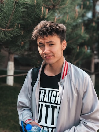 Young person holding an Aquabox bottle outdoors, smiling under natural sunlight.
