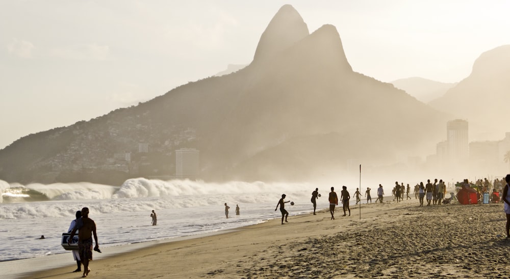 um grupo de pessoas em pé em cima de uma praia de areia