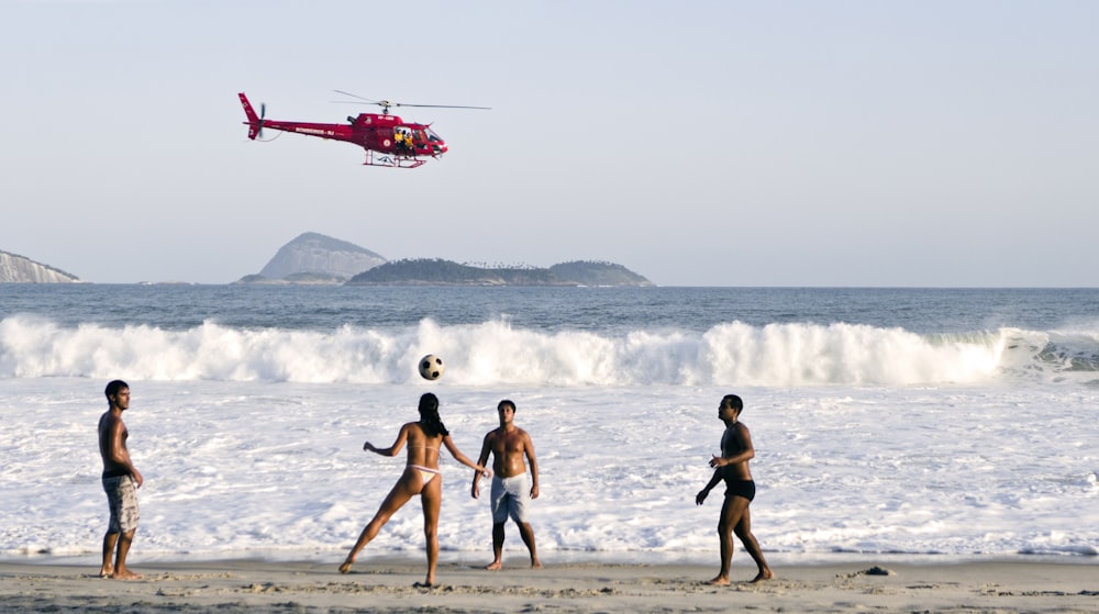 un grupo de personas en la playa jugando con una pelota de fútbol