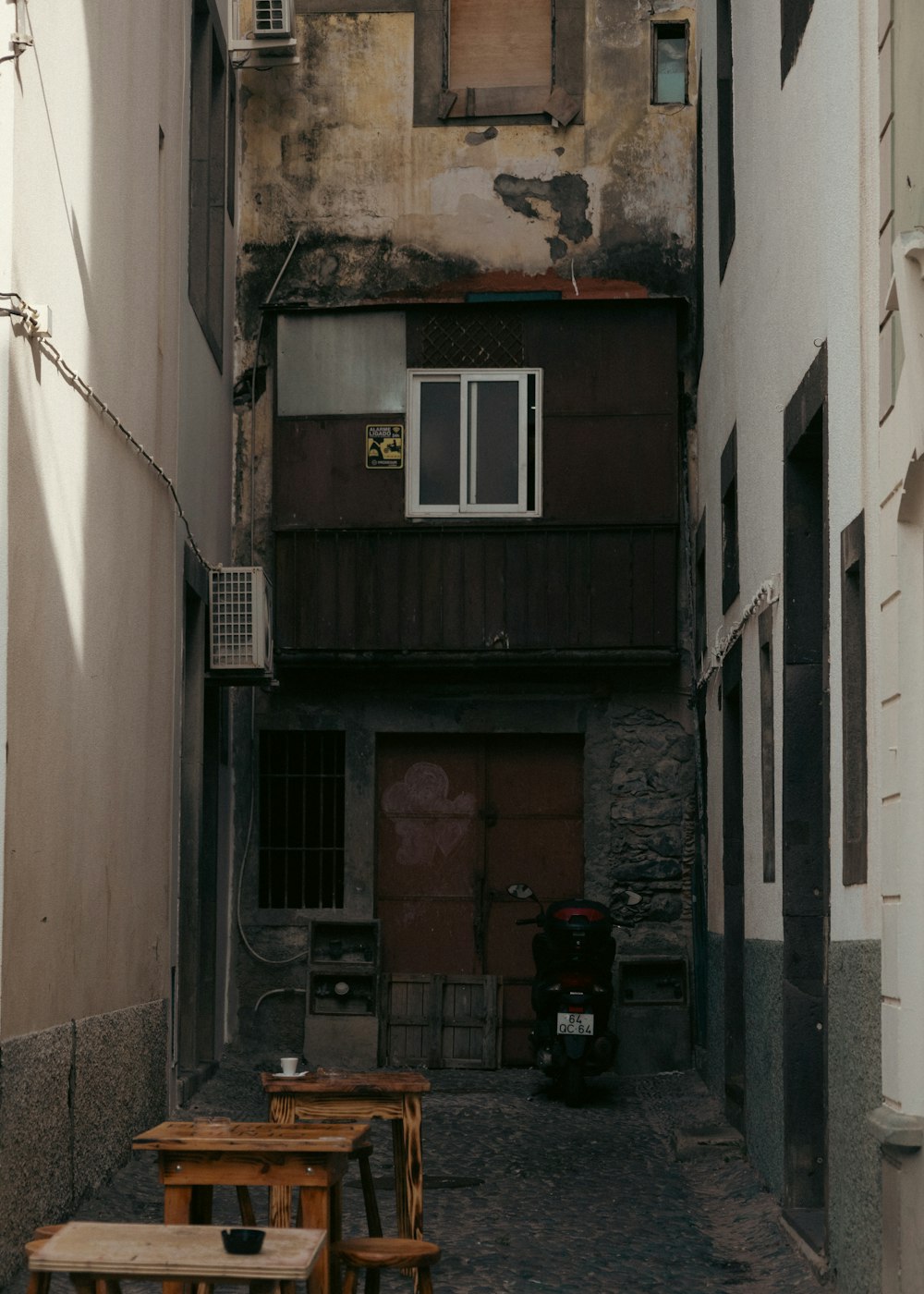 a narrow alley way with tables and chairs