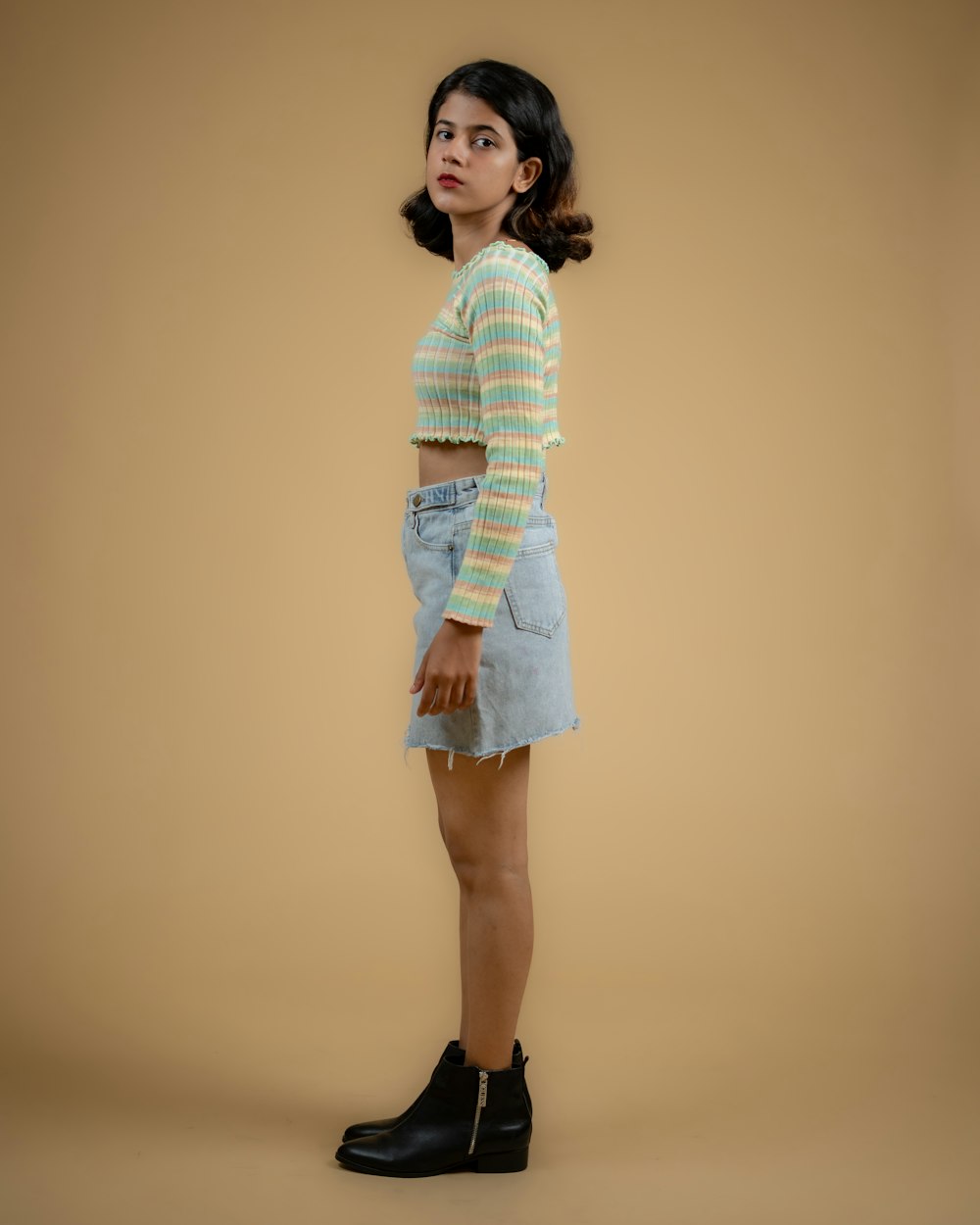 a young girl in a striped shirt and denim skirt