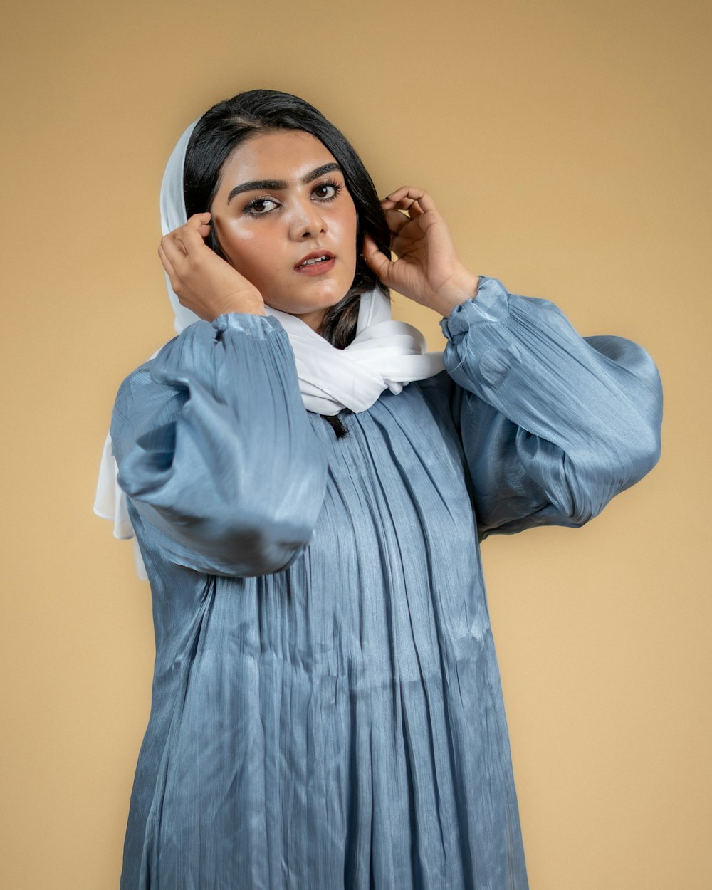 a woman wearing a blue dress and a white scarf