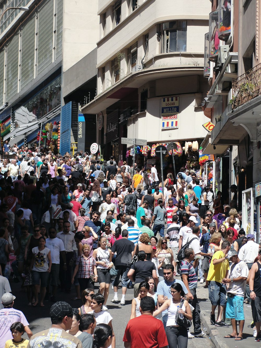 a crowd of people walking down a street next to tall buildings