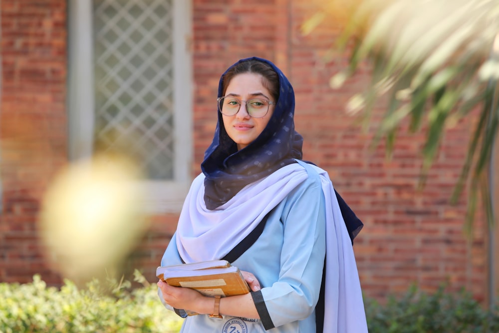 a woman in a blue hijab holding a book