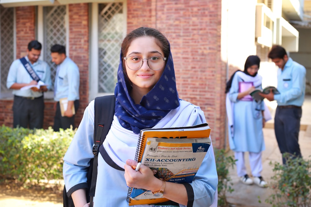 a woman in a hijab is holding a book