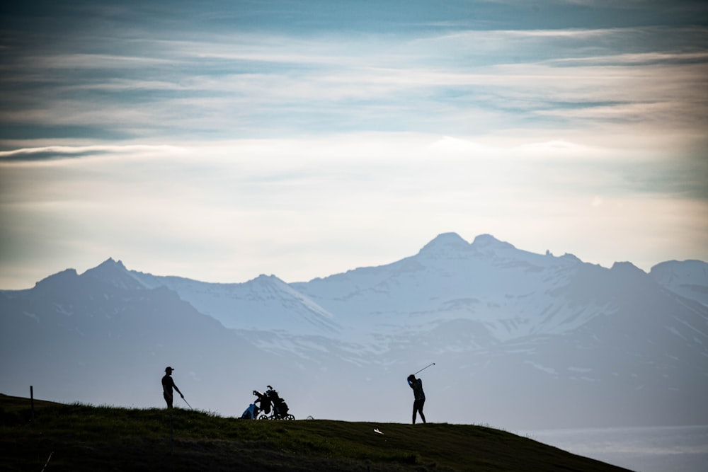 a group of people standing on top of a lush green hillside