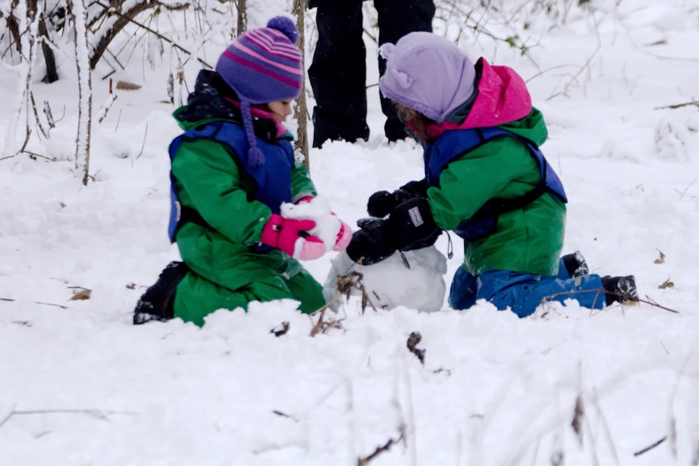 two children playing in the snow with a snowman