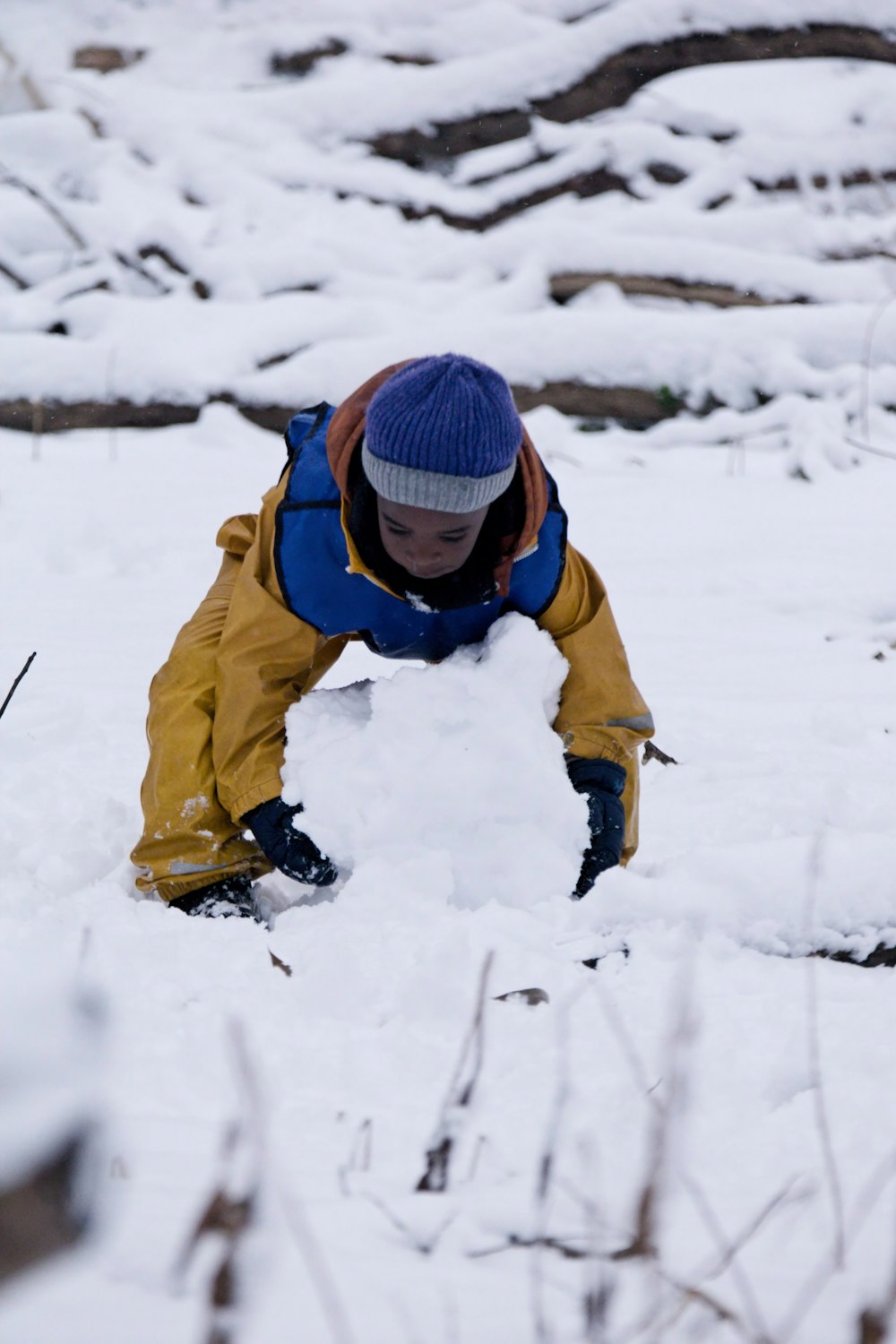 un jeune garçon construisant un bonhomme de neige dans la neige