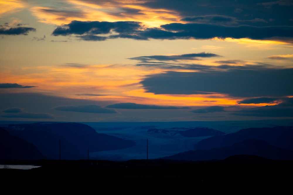 the sun is setting over a mountain range