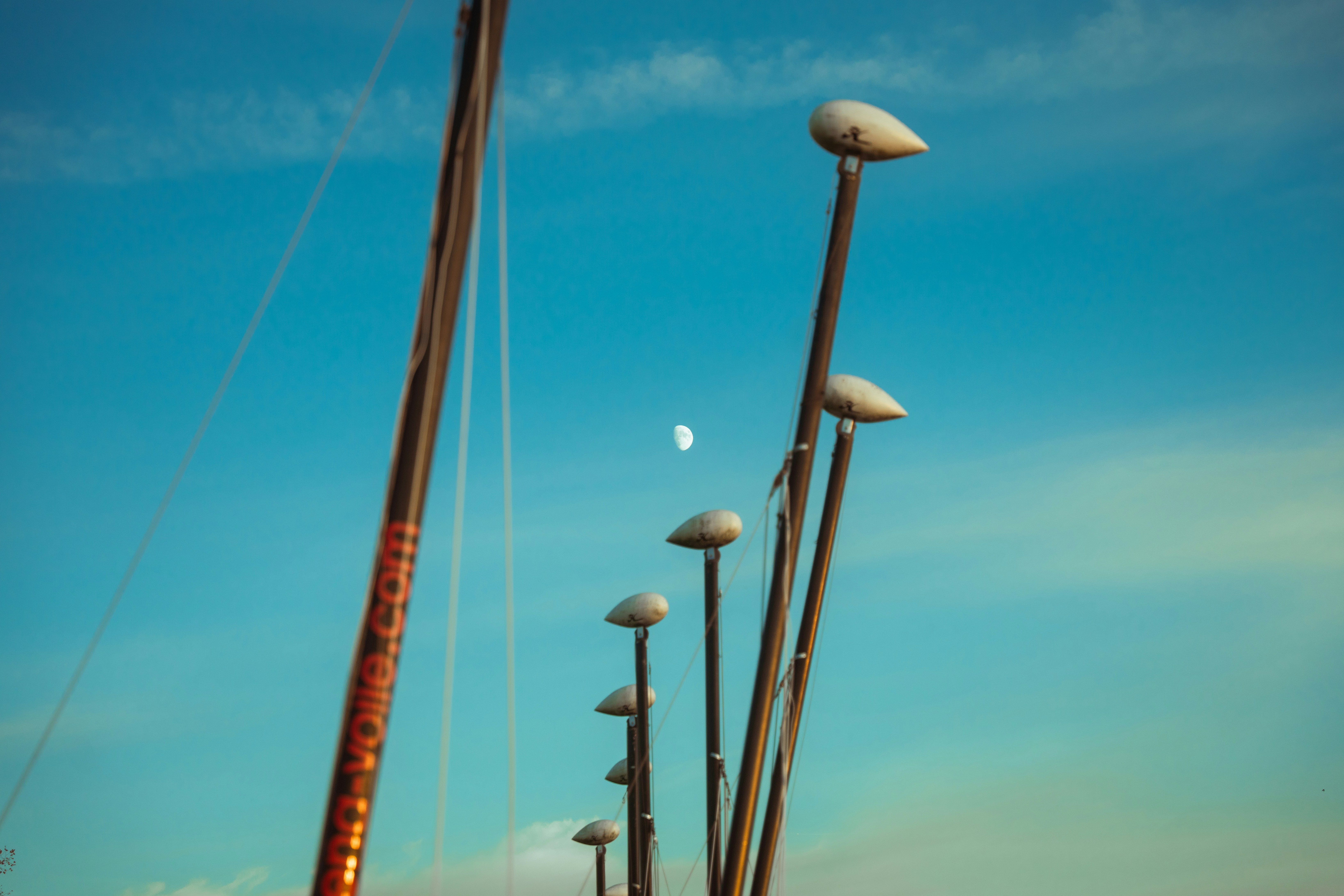 a row of sailboats sitting next to each other under a blue sky