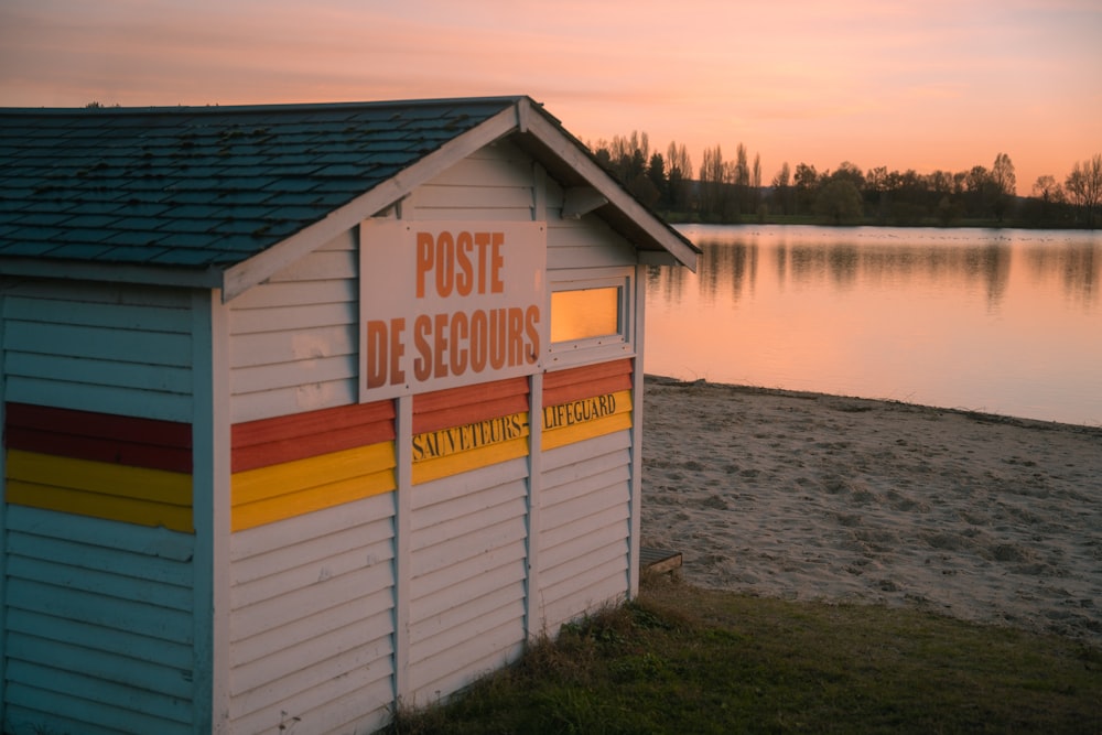 a small beach hut sitting on the shore of a lake