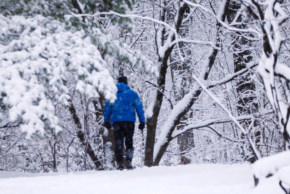 a man walking through a snow covered forest