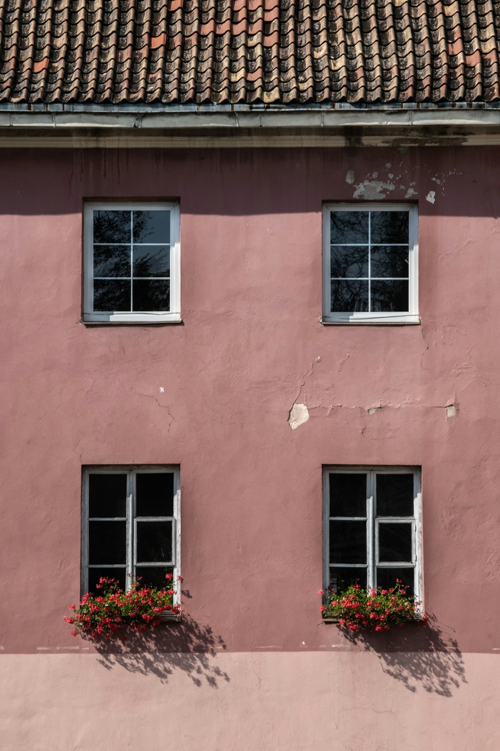 a pink building with three windows and a clock