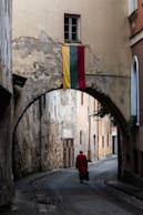 a person walking down a street under an arch