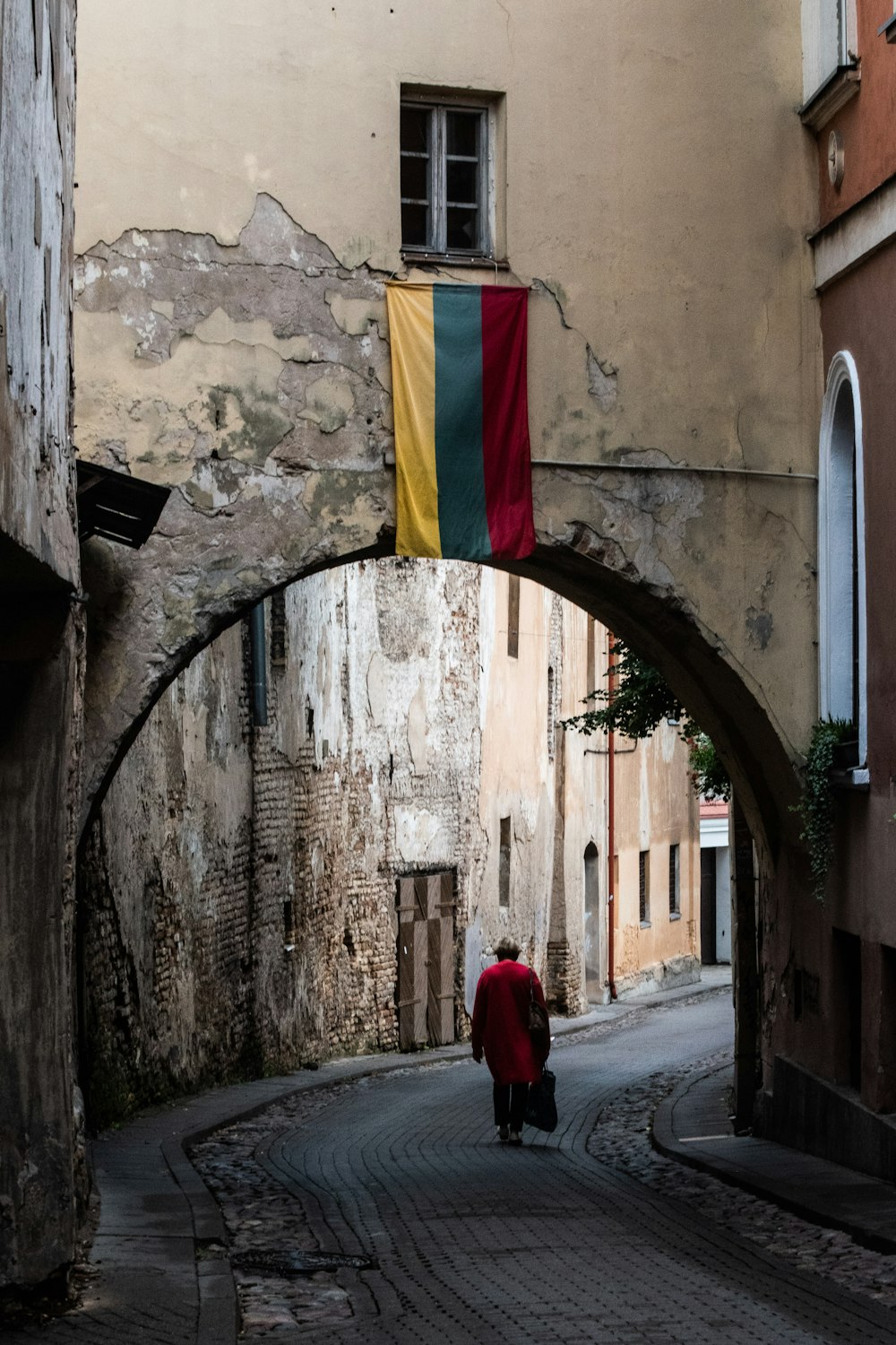a person walking down a street under an arch