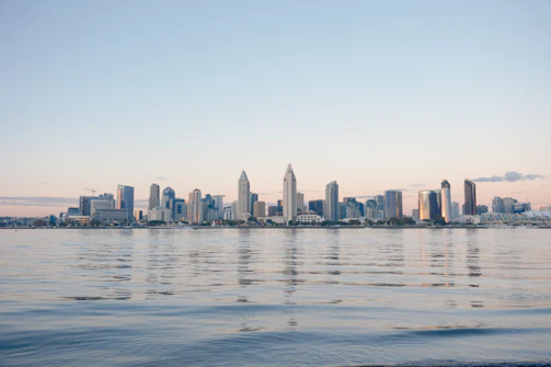 Modern city skyline at dusk with warm golden light reflecting off glass buildings.