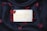 A bar of soap imprinted with 'Baylis & Harding England' placed on a black fabric background, surrounded by scattered red petals.