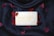A bar of soap imprinted with 'Baylis & Harding England' placed on a black fabric background, surrounded by scattered red petals.