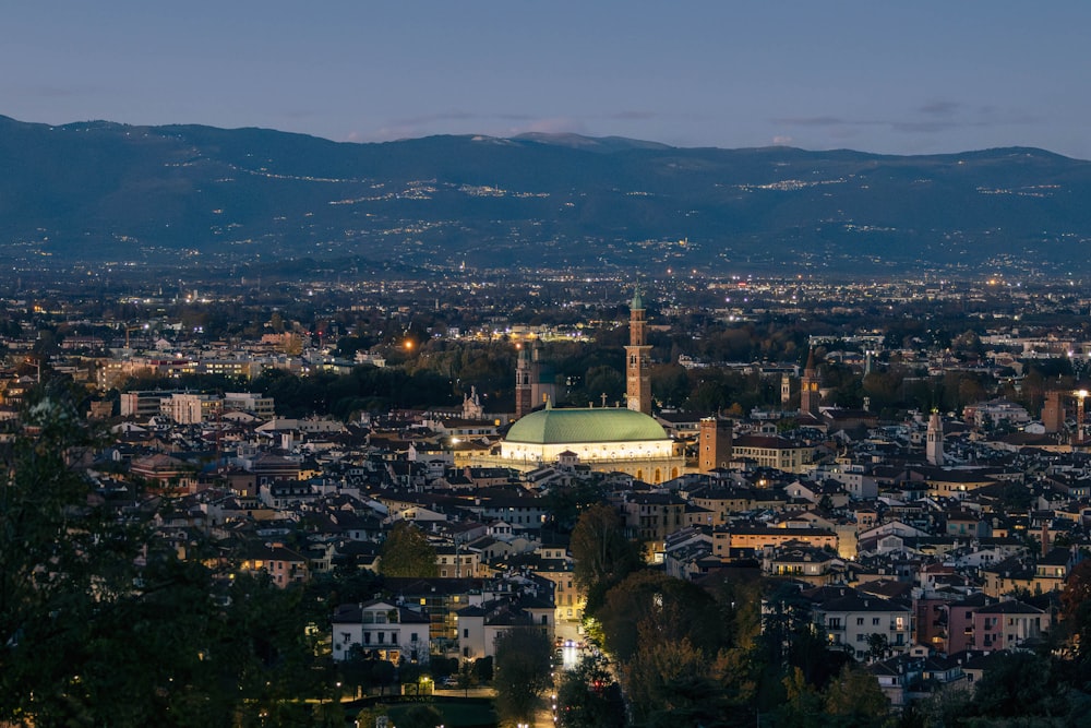 Una vista de una ciudad por la noche con montañas al fondo