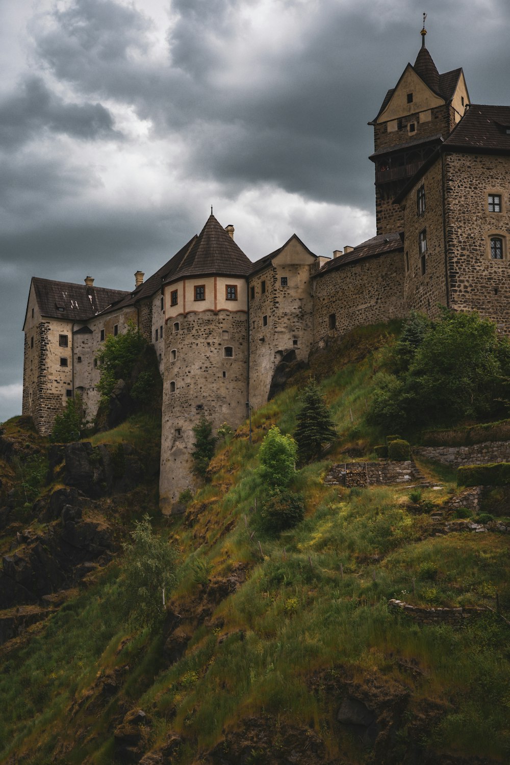 a castle on top of a hill under a cloudy sky