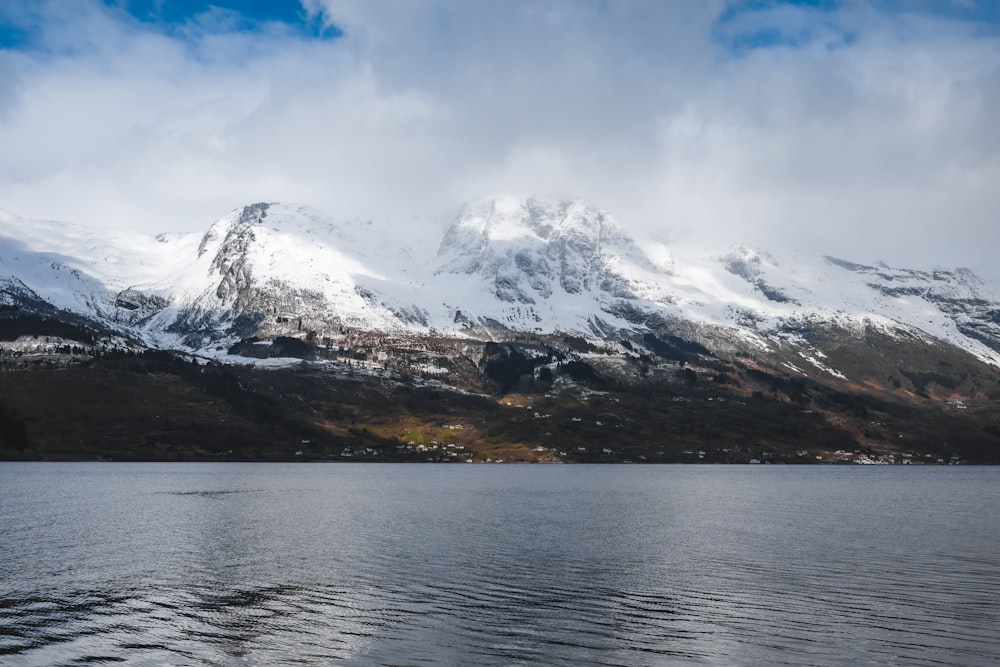 a large mountain covered in snow next to a body of water