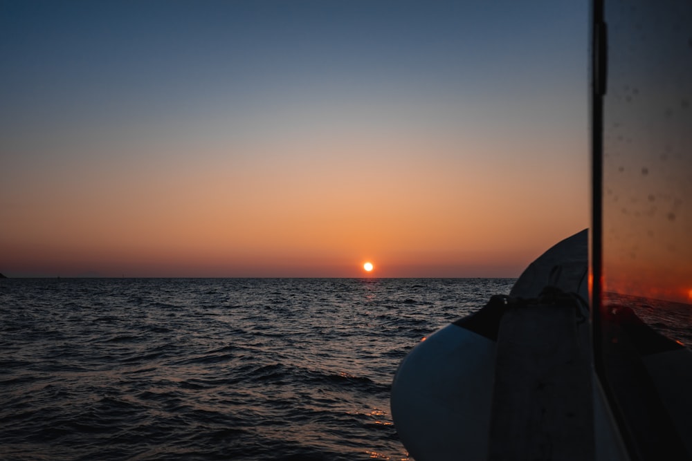 the sun is setting over the ocean as seen from a boat